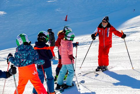 Moniteur de ski avec son groupe d'enfant en leçon de ski