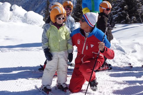 Un moniteur de ski avec un enfant au club piou-piou
